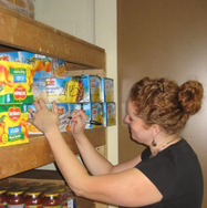 Image of pantry volunteer stocking shelves with food items