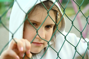 Image of young girl looking through a fence