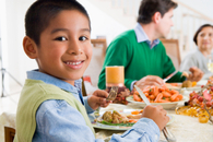 Image of boy eating dinner with his family