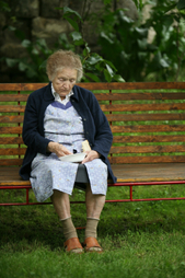 Image of elderly woman eating on a park bench
